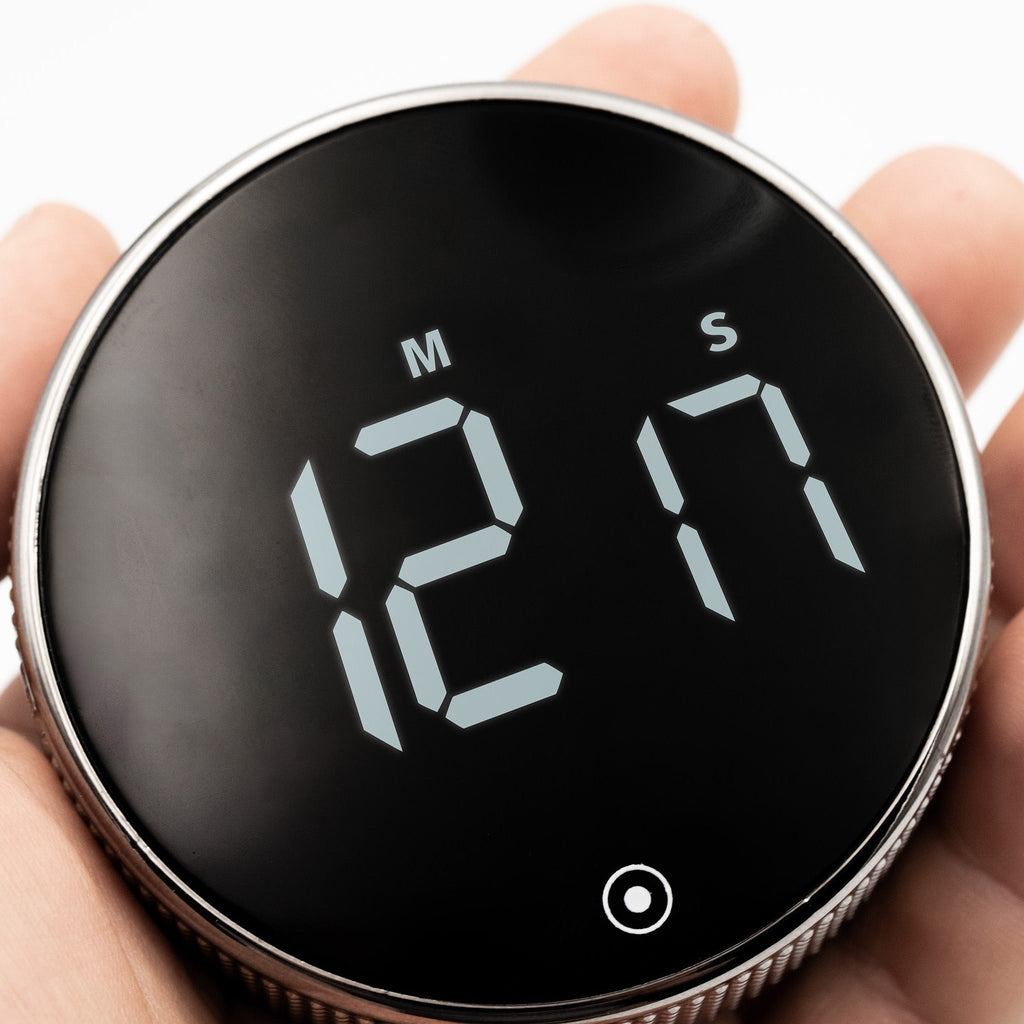 New Nordic Time fokusur holdt i hånden, der viser det digitale display og fremhæver urets kompakte størrelse og elegante design med tekstureret ramme.