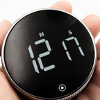 New Nordic Time fokusur holdt i hånden, der viser det digitale display og fremhæver urets kompakte størrelse og elegante design med tekstureret ramme.